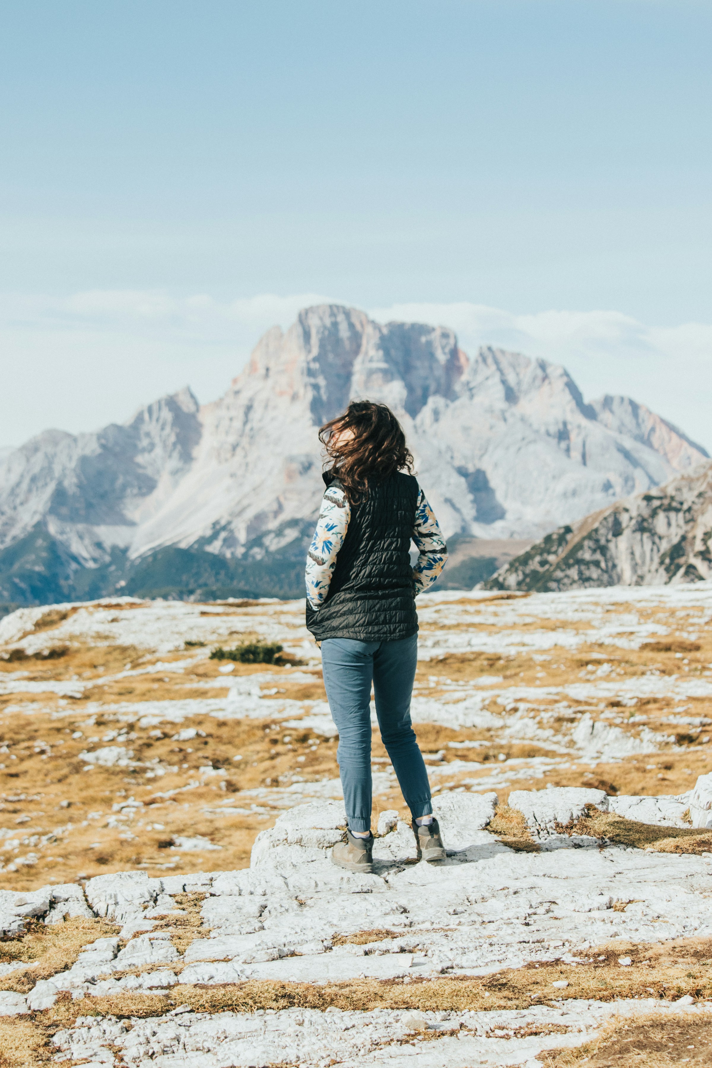 A woman standing on a mountain ridge, looking out at the landscape — she got here at her own pace.